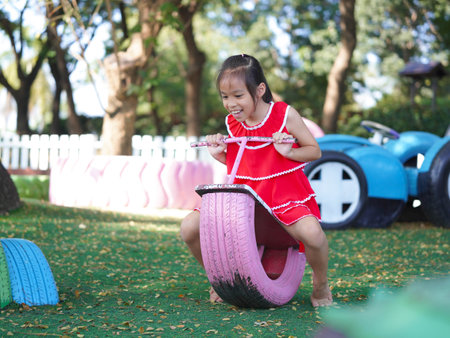 Cute girl playing in the playground during summer vacation. Happy children having fun in an outdoor park.の写真素材