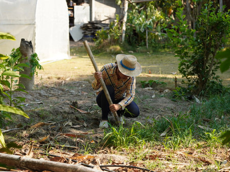 Asian adult woman working outdoors in summer garden.