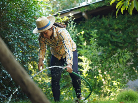 Asian adult woman working outdoors in summer garden.の写真素材