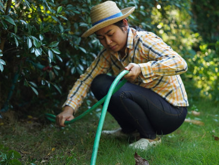 Asian adult woman working outdoors in summer garden.