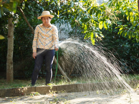 Asian adult woman working outdoors in summer garden.の写真素材
