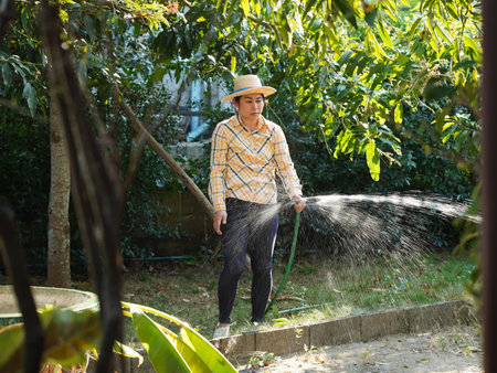 Asian adult woman working outdoors in summer garden.の写真素材