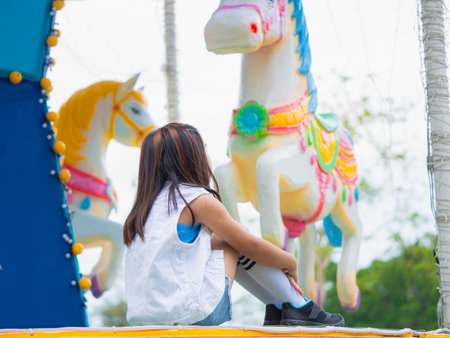 Asian girl having fun in amusement park, enjoying carousel on family vacation.の写真素材