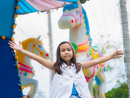 Asian girl having fun in amusement park, enjoying carousel on family vacation.の写真素材