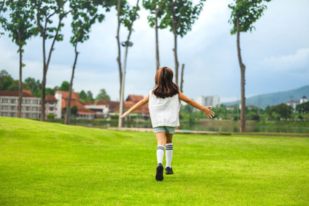 A cute and happy little girl is playing and running around the park on a beautiful morning.の写真素材