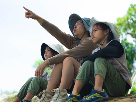 Asian mother takes her children to learn about nature in the forest to explore nature from the real place. Mother and children are enjoying nature outdoors, adventuring in the forest.の写真素材