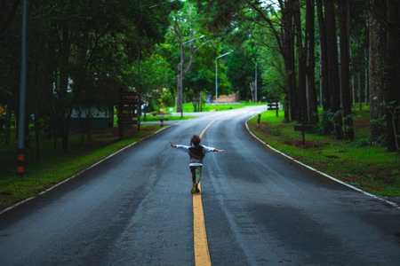 Happy little girl tourist walking on asphalt road outdoors enjoying beautiful nature of forest in national park on spring vacation.の写真素材