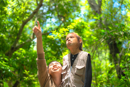 Asian mother takes her daughter to learn about nature in the forest to explore nature from the real place. Mother and daughter are enjoying nature outdoors, adventuring in the forest.の写真素材