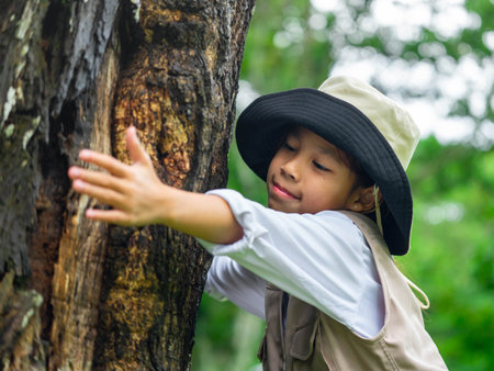 Little ecologist child is gently hugging the trunk of a tree in a forest park. Love Natureの写真素材