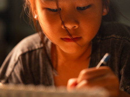 Close up of cute asian girl hand holding pencil drawing on white paper at home.の写真素材