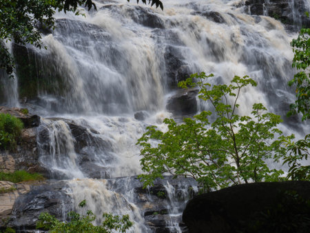The nature of the waterfall in the forest that flows strongly during the rainy season. Strong current in the river, waters turned muddy after heavy rains in autumn.の写真素材