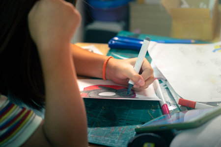 Asian girl drawing with magic markers on paper at home, close-up of hands, childhood creativity and...