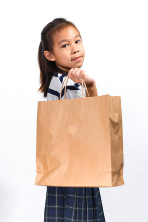An Asian girl holding a brown paper bag and looking at the camera, symbolizing shopping and eco-friendly lifestyle.の写真素材