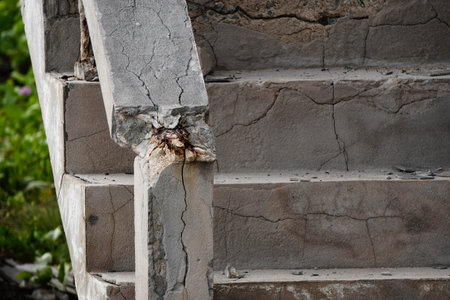 Old concrete column with visible cracks and corrosion, showing structural weakness and aging construction.の写真素材