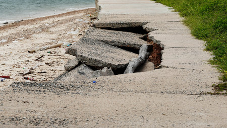 Cracked and collapsed coastal road severely damaged by sea erosion and flooding.の写真素材