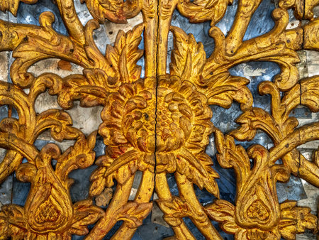 Close-up of traditional Thai gold gilded wood carving pattern with floral design, symbolizing fine craftsmanship, temple decoration, and cultural heritage.の写真素材