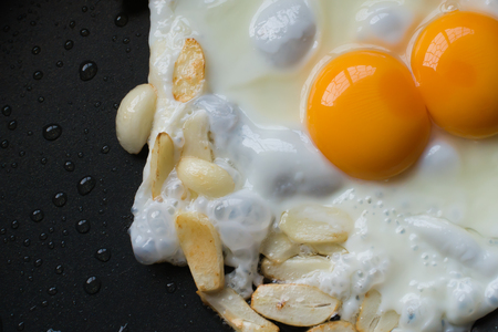 Fried twin egg and slide galic on hot panの写真素材