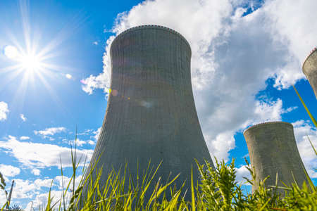 Close-up shot of a cooling tower of nuclear power plant behind green grass. In a beautiful sunny day.の写真素材