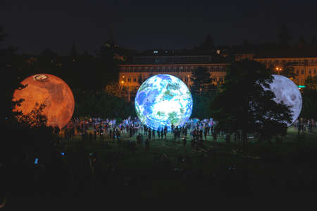 BRNO, Czech Republic - August, 14. 2020 Giant inflatable model of the planets Mars, Earth and Moon at night with silhouettes of people. Solar system research.のeditorial素材