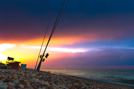 Beautiful sunset over the sea. Fishing rods on the shore of the sea against the background of a...
