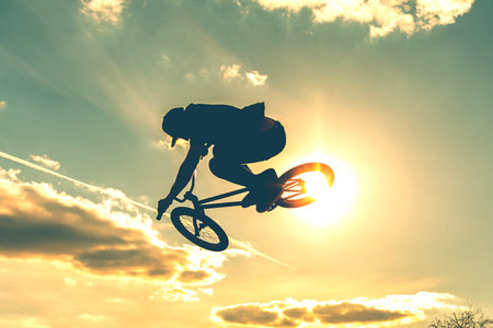 Man on bmx bike against sunshine sky. High BMX jump. Biker silhouette doing an jump.の写真素材