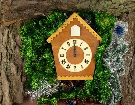 Vintage cuckoo clock Christmas background. Top view of pine bark and New Year's garlands.