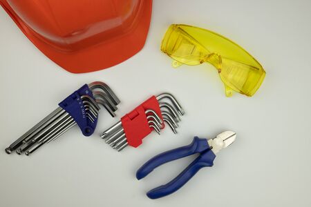 orange safety helmet, tools and safety glasses on a white background - top view