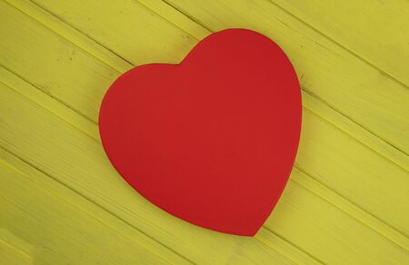large figure of a heart, red on a yellow wooden background from boards-close-upの写真素材