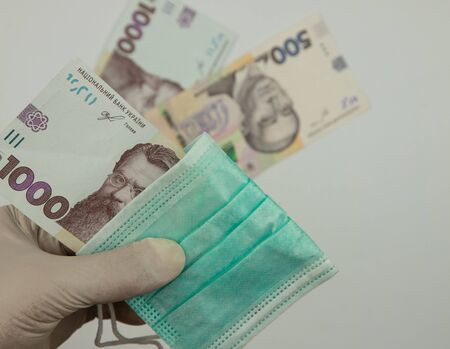 the impact of the pandemic on the economy of Ukraine, a bill of 1000 hryvnias, a medical mask in a...