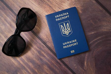 Glasses and international passport of Ukraine on the wooden background. Travel and visa free concept.の写真素材