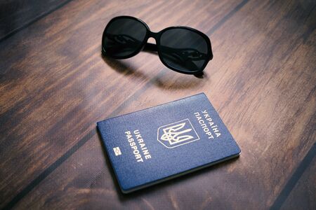 International passport of Ukraine and glasses on background with wooden texture. Travel, vacation and visa free concept.の写真素材