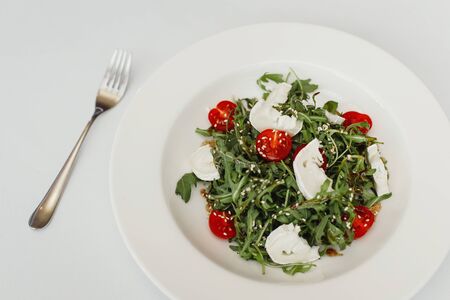 Fresh salad with arugula, cherry tomatoes, mozzarella cheese and walnuts on white . Top viewの写真素材