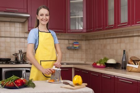 A pretty young woman cutting vegetables in a kitchenの写真素材