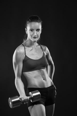 young fit woman lifting dumbell, monochrome photoの写真素材