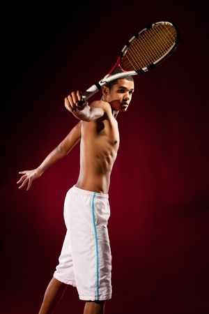 Young tennis player with racket hitting a tennis ballの写真素材