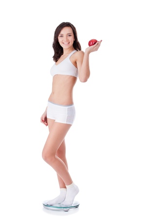 Yound fit girl holding apple standing on scalesの写真素材