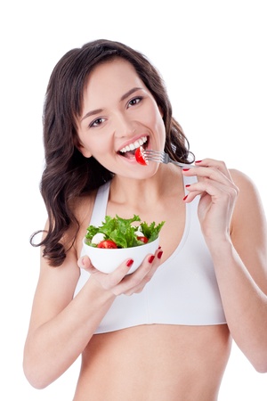 Young sportive girl eating green salad; isolated on whiteの写真素材