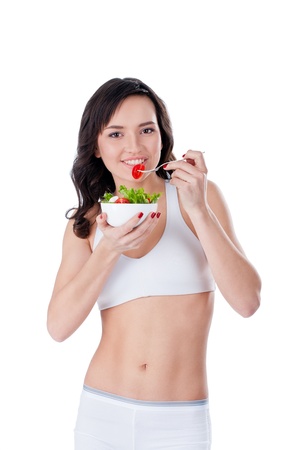 Young sportive girl eating green salad; isolated on whiteの写真素材