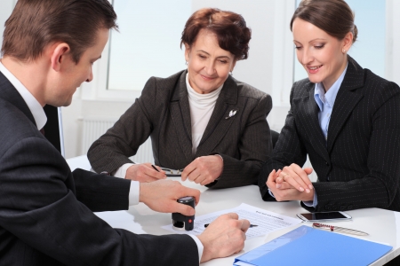 Agent  or notary public  signing documents with with senior woman and her daughterの写真素材
