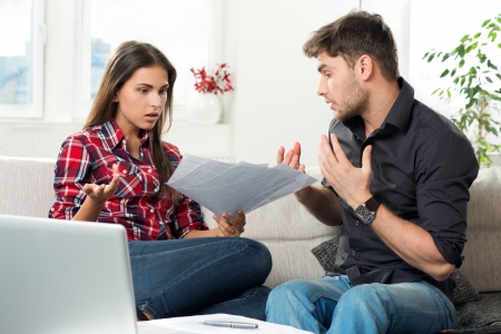 quarreled young couple with unpaid bills in their living roomの写真素材