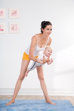 young mother does physical fitness exercises together with her babyの写真素材