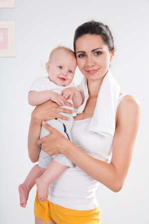 A mother with a towel around his neck after fitness exercise with babyの写真素材