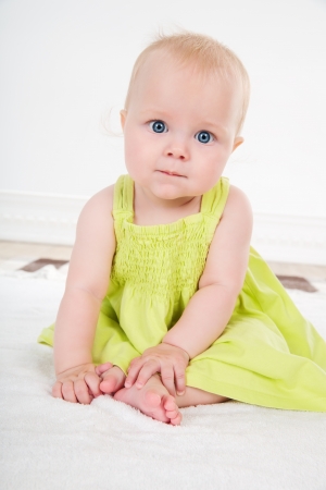 pretty baby girl with big blue eyes sits in  green dress の写真素材