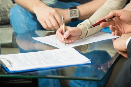 Hands of people signed the document, sitting at the deskの写真素材