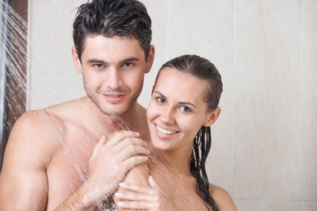 Young couple washing their heads in the showerの写真素材