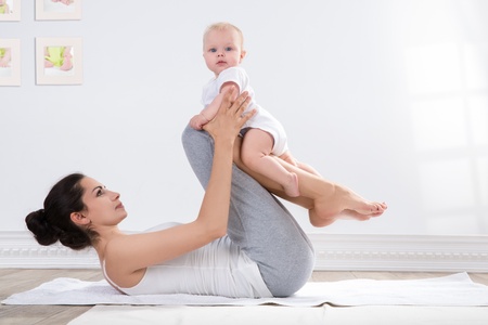 young mother does physical yoga exercises together with her babyの写真素材