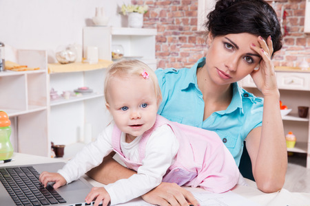 Young business woman with laptop and her baby girlの写真素材