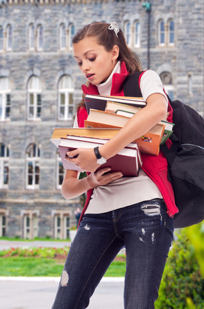 Young beautiful girl student holding a lot of booksの写真素材