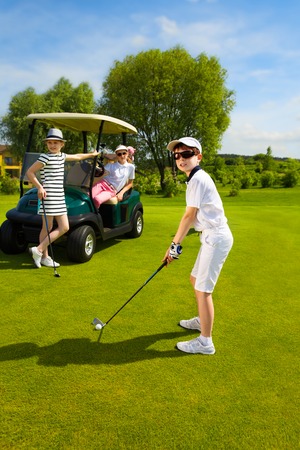 Children playing golf and taking part on kids competition in golf course at summer dayの写真素材