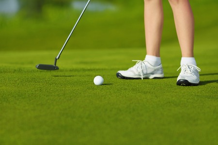 Golf ball, putter and boy's legs on greenの写真素材
